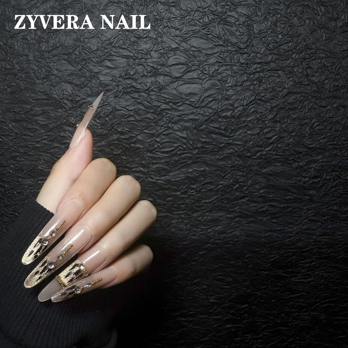 nude black gold abstract almond press-on nails worn on hand